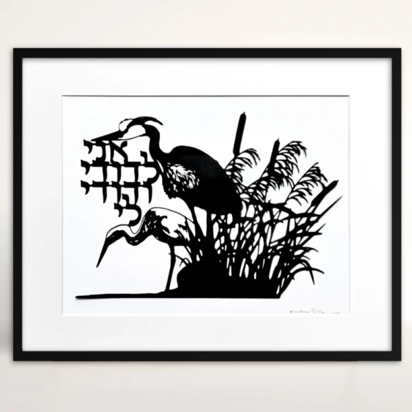 Black papercut artwork depicting two herons in a marsh setting with cattails and reeds. The artwork includes Hebrew text and is set against a white background. The herons are in silhouette.