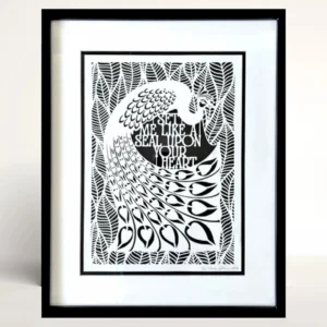 The peacock in the middle of the papercut is surrounded by broad leaves. The English text for the quote sits between the peacock's curved tail and body. By Evelyn Goldman Art