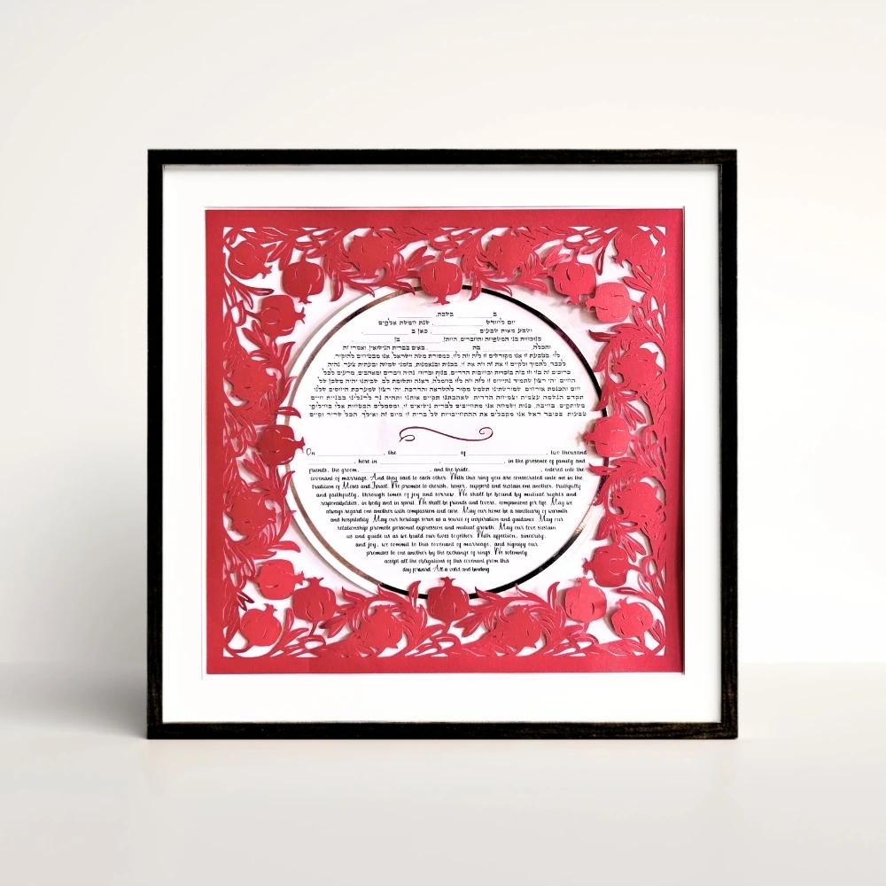 red pomegranate papercut border around circle ketubah in a black frame.