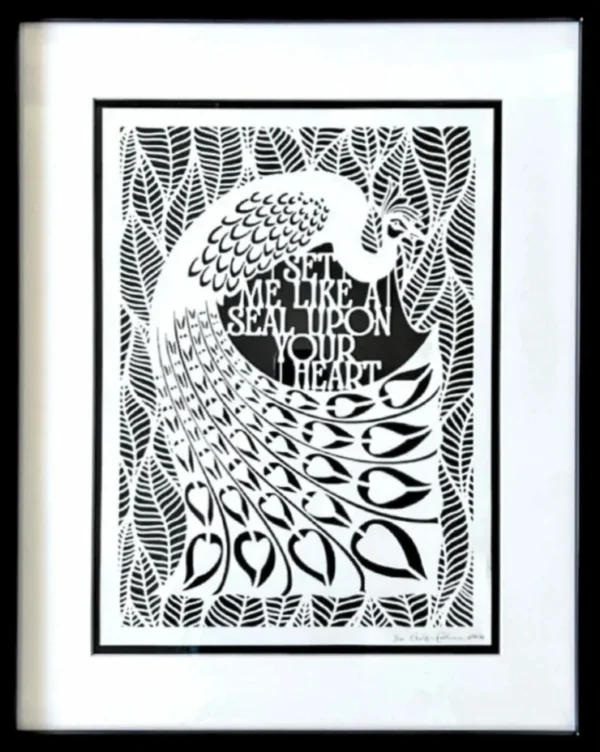 The peacock in the middle of the papercut is surrounded by broad leaves. The English text for the quote sits between the peacock's curved tail and body. By Evelyn Goldman Art