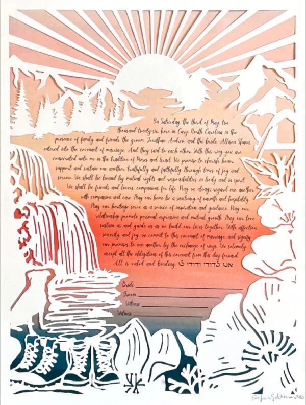 A paper-cut artwork ketubah depicts mountains, trees, a waterfall and river, a pair of boots, a dog, and a tent with a handwritten marriage contract at the center, beneath a sunrise.